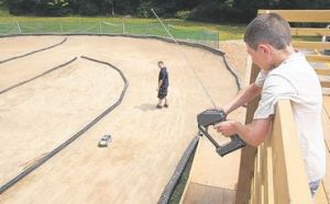 Dominick Guardino, 9, of Middletown, drives a remote-controlled car Thursday on the new track behind the Mechanicstown Fire Department Station No. 2 in the Town of Wallkill. Firefighter George Rosado stands on the track, which will officially open to the public on Saturday. Times Herald-Record/TOM BUSHEY